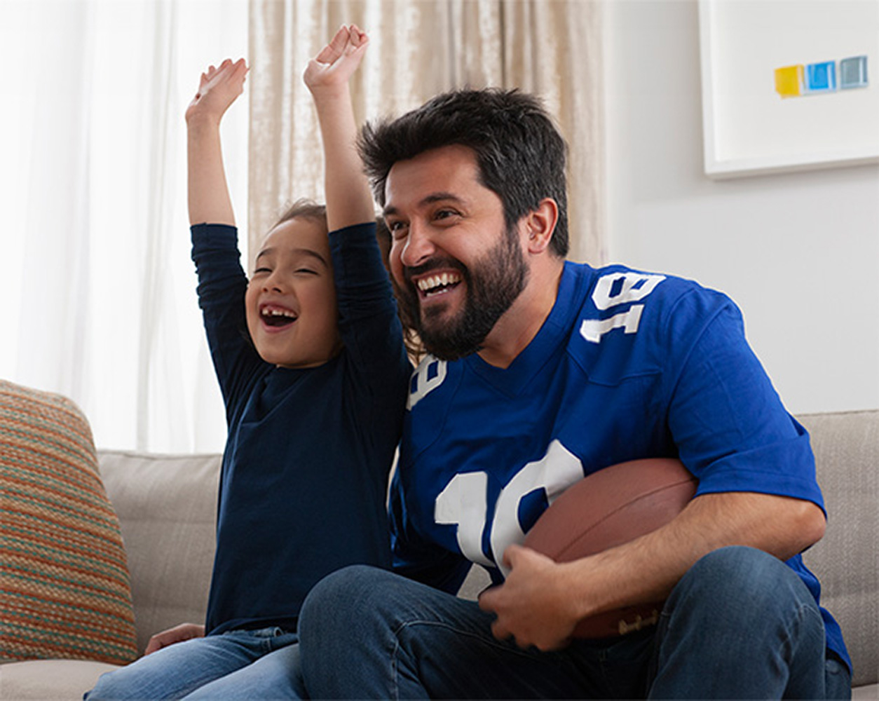 A father and daughter watching football at home.