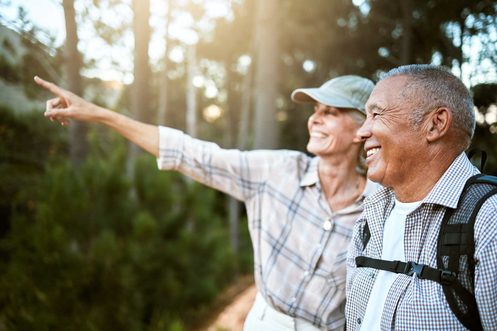 Hiking, adventure and freedom with a senior couple enjoying and exploring the forest or woods and bonding together. Happy, carefree and exploring retired man and woman looking at the views outdoors.