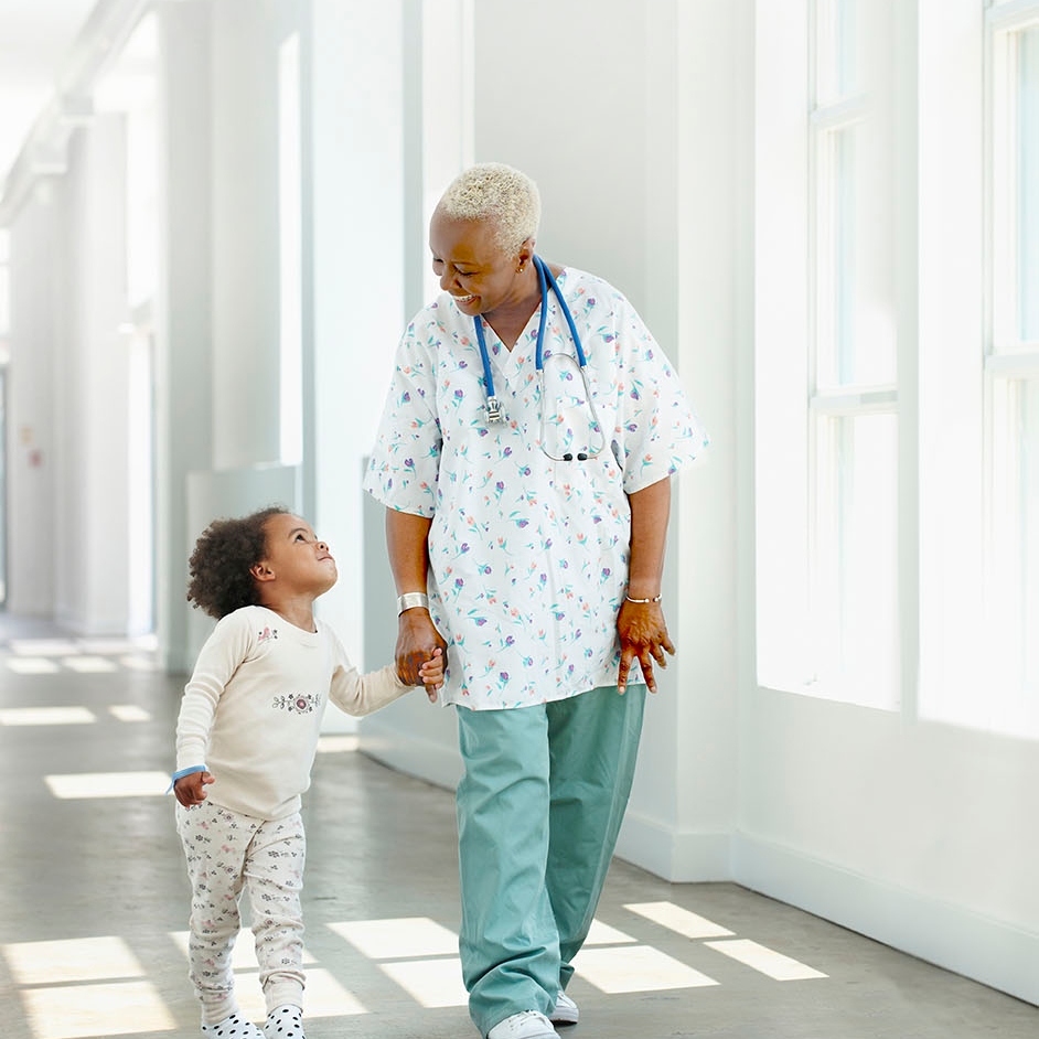 Enfermera tomando de la mano a un niño en un hospital.