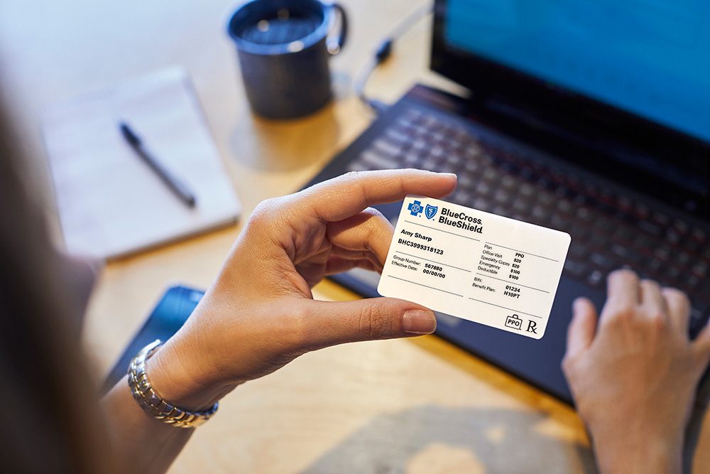  A lady holding up their benefits card with typing. 