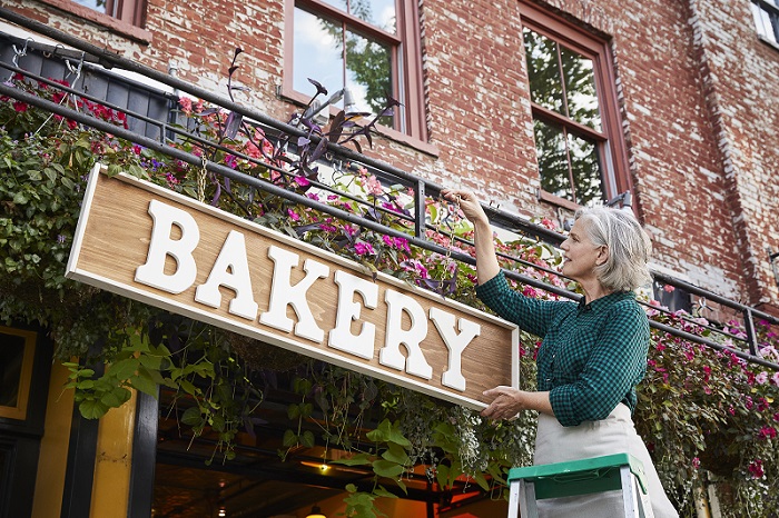 A woman hanging a bakery sign.