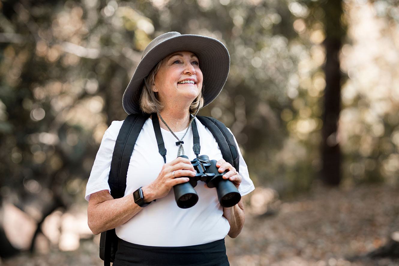 Mujer mayor activa que usa binoculares para ver la belleza de la naturaleza