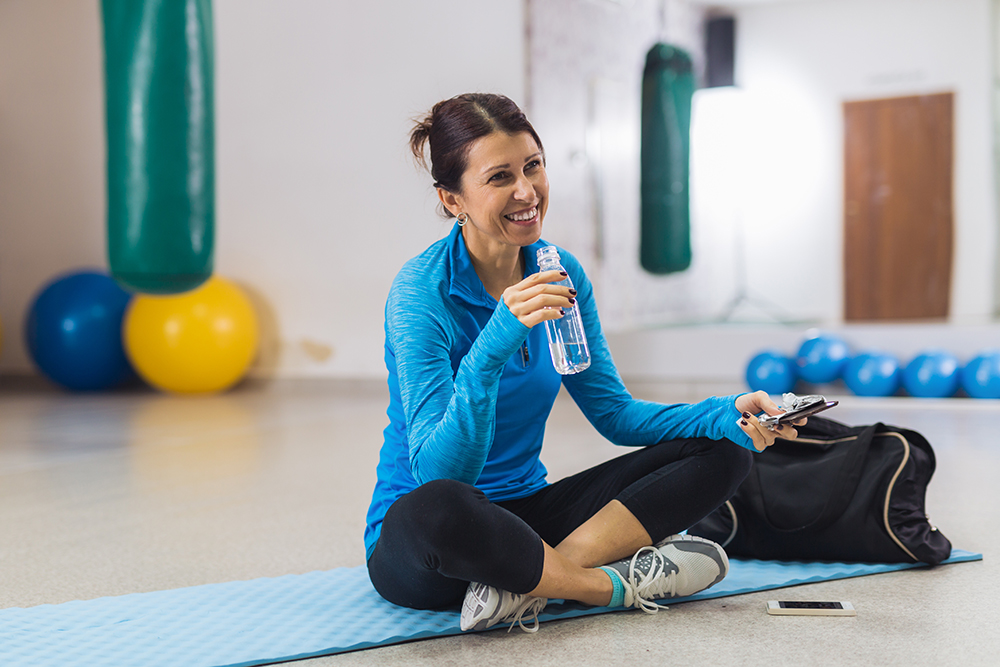 Mujer sonriendo con ropa de entrenamiento en el gimnasio.