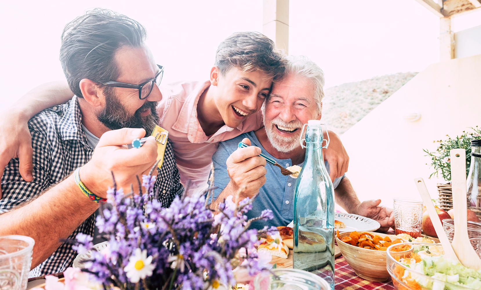 Grandfather, father and young teenager son all together eating at lunch. 